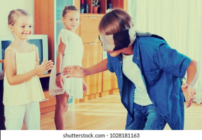 Cheerful children playing with blindfold in the living room. Focus on boy