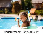 Cheerful children playing waterguns, rejoicing, jumping, swimming in pool.