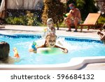 Cheerful children playing waterguns, rejoicing, jumping, swimming in pool.