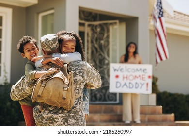 Cheerful children reuniting with their military dad. Two happy young children embracing their father upon his return from the army. American serviceman receiving a warm welcome from his family. - Powered by Shutterstock