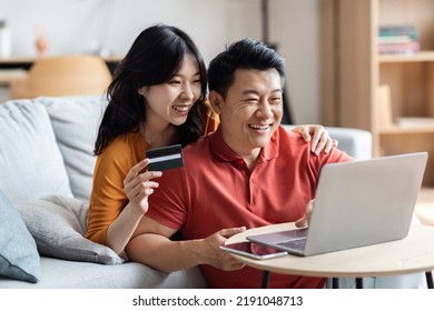 Cheerful chinese man and woman embracing, using modern laptop and plastic credit card, happy asian spouses paying for goods and services online while staying home, copy space - Shutterstock ID 2191048713