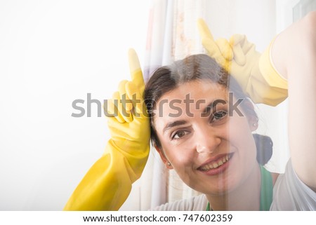Cheerful cleaning woman acting funny and washing the house window