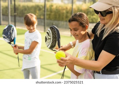 Cheerful coach teaching child to play tennis while both standing on tennis court - Powered by Shutterstock