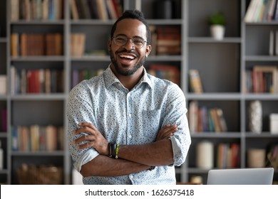Cheerful confident handsome african american young adult businessman professional teacher hipster entrepreneur laughing looking at camera standing arms crossed at home office, business portrait - Shutterstock ID 1626375418