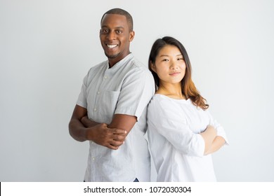 Cheerful confident young multiethnic student standing back to back and looking at camera. Positive interracial friends being leaders. Team concept