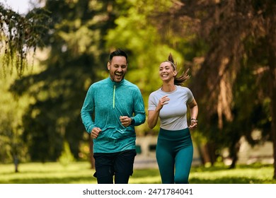 Cheerful couple of athletes running during sports training in the park. Copy space. - Powered by Shutterstock