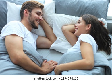 Cheerful Couple Awaking And Looking At Each Other In Bed.