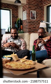 Cheerful Couple Browsing Internet On Mobile Phone And Watching Tv, Eating Takeaway Fast Food From Takeout Delivery. Dinner Meal Package To Eat And Watch Movie On Television Together.