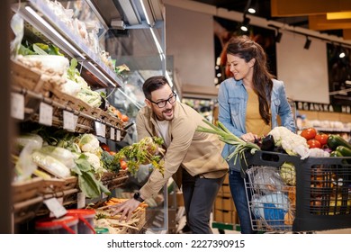 Cheerful couple is buying vegetables in hypermarket. - Powered by Shutterstock