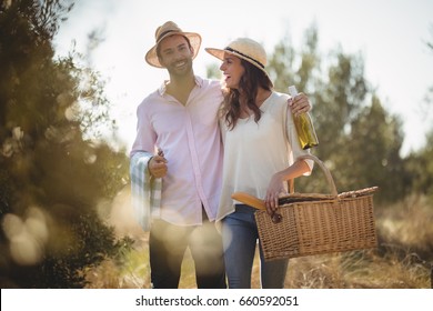 Cheerful couple carrying picnic basket at olive farm - Powered by Shutterstock