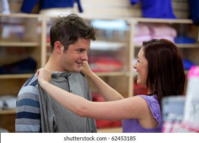 Cheerful Couple Choosing Clothes Standing In The Men Department In A Shop