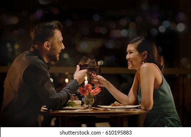 Cheerful Couple Clinking Glasses At Late Romantic Date In Restaurant