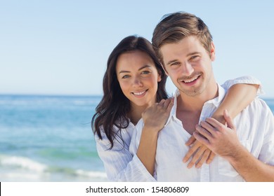 Cheerful couple embracing and posing on the beach on a sunny day - Powered by Shutterstock