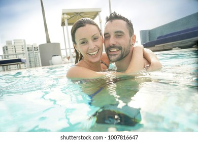 Cheerful couple enjoying bath in resort swimming pool - Powered by Shutterstock