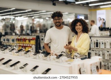 A cheerful couple exploring options at an electronics store's smartphone section, comparing devices enthusiastically. Bright ambiance enhances a friendly, modern shopping experience for various 