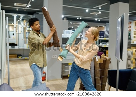 Cheerful couple fighting with cushion in store