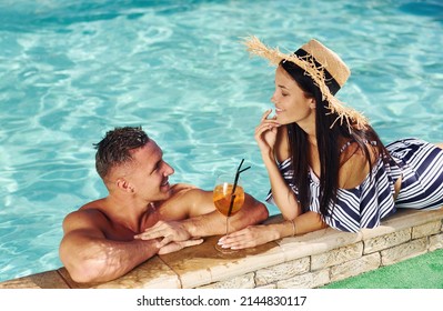 Cheerful couple or friends together in swimming pool at vacation.