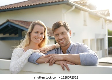 Cheerful Couple In Front Of New House