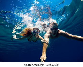 Cheerful couple having fun underwater and making selfie. - Powered by Shutterstock