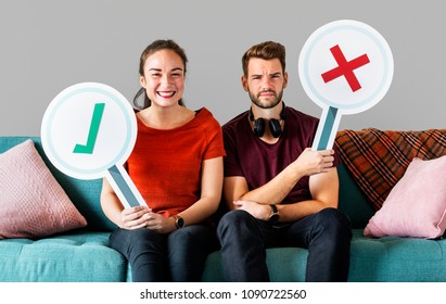 Cheerful couple holding vote icon sitting on a couch