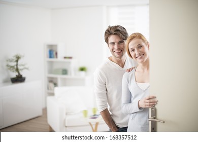 Cheerful Couple Inviting People To Enter In Home