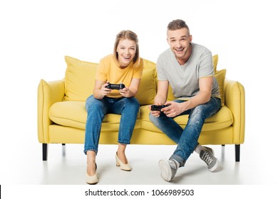 Cheerful Couple With Joysticks Playing Video Game While Sitting Together On Yellow Sofa, Isolated On White