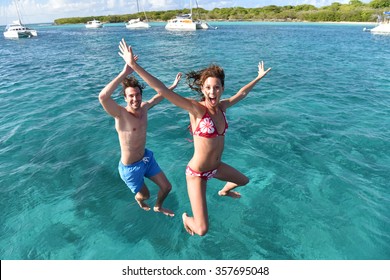 Cheerful couple jumping into water from boat