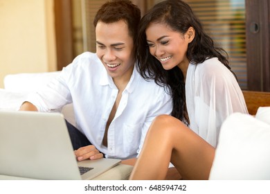 Cheerful couple with laptop, together enjoying and smiling 