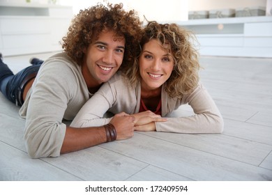 Cheerful Couple Laying Down On Wooden Floor