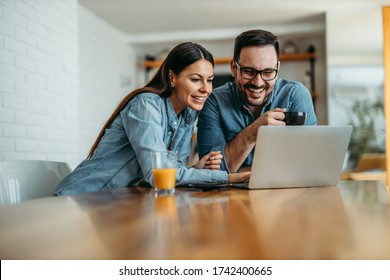 Cheerful couple looking pictures on laptop computer, copy space, portrait.