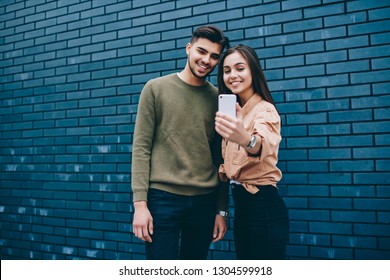 Cheerful Couple In Love  Dressed In Casual Posing For Selfie On Smartphone Camera Standing Together,young Smiling Teen Hipster Girl And Guy Using Modern Mobile Phone Application Making Common Picture