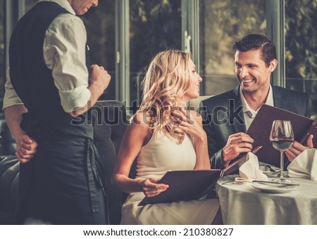 Cheerful couple with menu in a restaurant making order