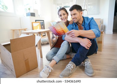 Cheerful Couple Moving In New Home, Choosing Wall Paint Colours