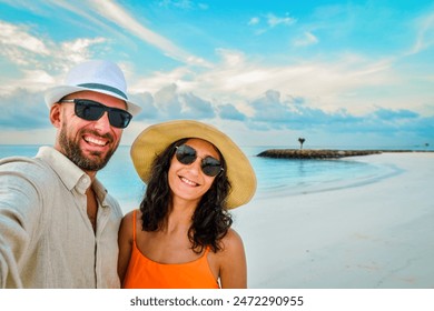 Cheerful couple on vacation in Maldives taking selfie on sandy tropical beach- Millennial guy and girl enjoying summertime day out smile at camera together - Powered by Shutterstock