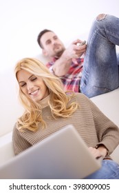 Cheerful couple relaxing together on couch surfing internet or watching TV