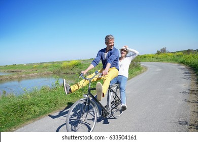 Cheerful Couple Riding Bike On A Sunny Day