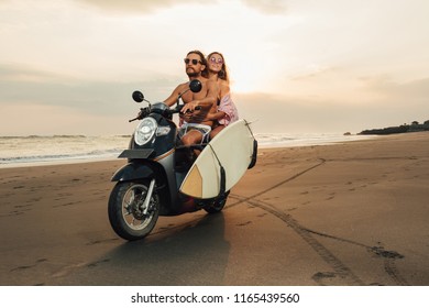 cheerful couple riding motorbike with surfboard on beach in bali, indonesia - Powered by Shutterstock