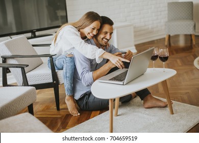 Cheerful Couple Searching Internet On Laptop In Living Room At Home