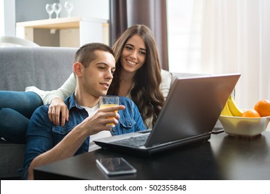 Cheerful couple searching something on laptop at home. - Shutterstock ID 502355848