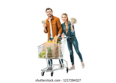 Cheerful Couple Showing Cash Money And Carrying Shopping Trolley With Food In Paper Bags Isolated On White