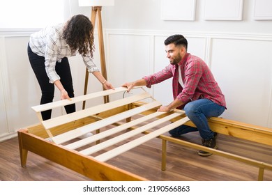 Cheerful Couple Smiling While Putting Together And Assembling A New Bed Frame While Doing Home Improvements
