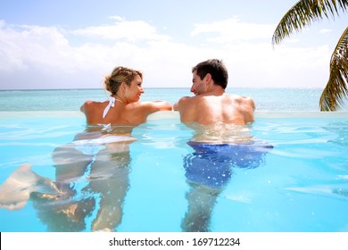 Cheerful Couple Swimming In Infinity Pool