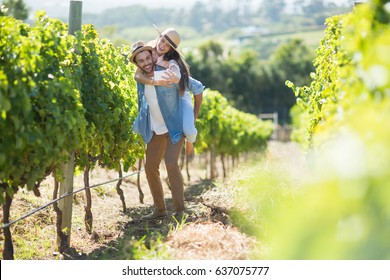 Cheerful couple taking selfie while piggybacking at vineyard during sunny day - Powered by Shutterstock