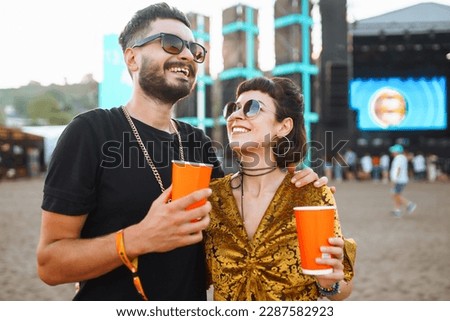 Cheerful couple together at the music festival. Young guys drink beer together and have fun at the beach music festival. Beach party, summer vacation.