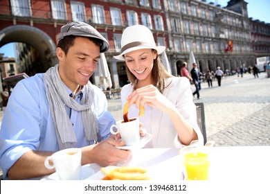 Cheerful Couple Of Tourists Eating Churros In Madrid