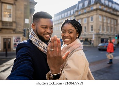 Cheerful Couple In Town, Woman Holging Hand Up To Show Engagement Ring