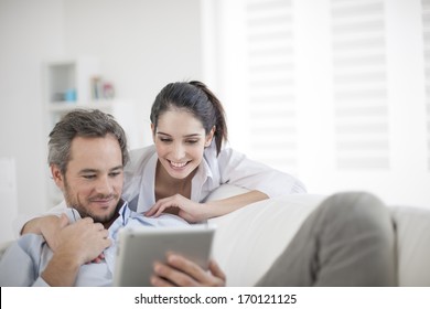 Cheerful couple using digital tablet at home
