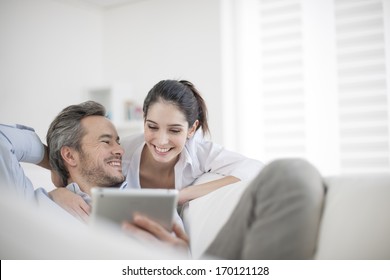 Cheerful Couple Using Digital Tablet At Home