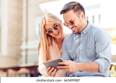 Cheerful Couple Using Digital Tablet Outdoors