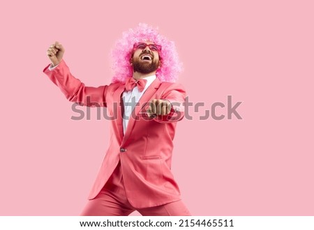 Cheerful crazy man in pink wig making funny dance moves isolated on pink background. Eccentric man in pink formal suit rejoices, has fun and dances in gangnam style. Banner.